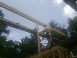 Carpenter setting a ridge beam over a new addition frame — Ice Dam Removal by Roofing Brothers in Malcom