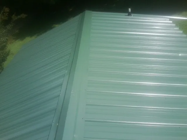 New green metal panels meeting at the ridge of a roof — Flat Roof Repair work by our crew in Malcom