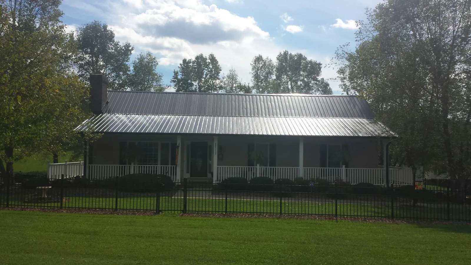 Gray metal roof on a brick ranch with a full width front porch — Gutter Guard Installation work by our crew in Malcom