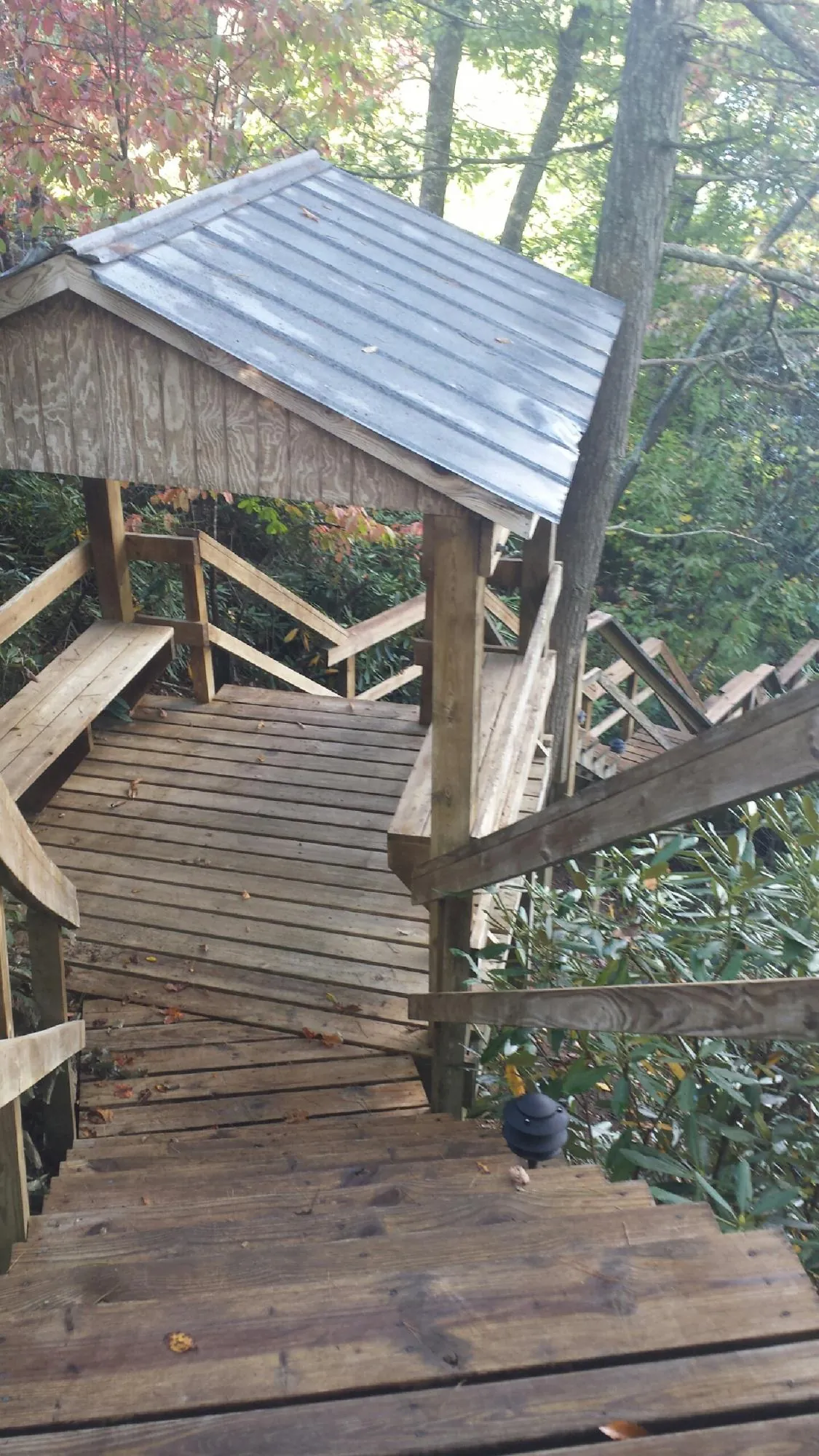 Metal roofed shelter over wooden steps on a wooded walkway — Skylight Repair & Installation work by our crew in Malcom