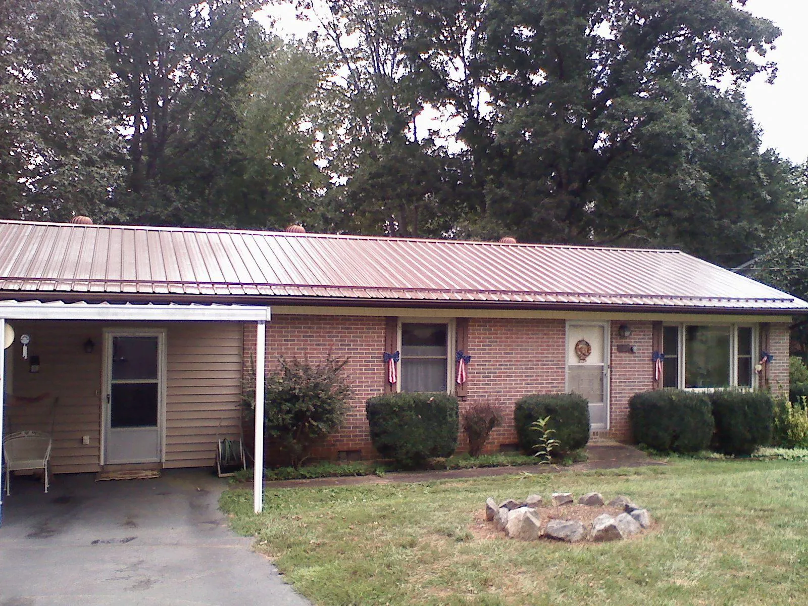 Bronze metal roof and carport on a brick ranch home — Roof Repair work by our crew in Malcom